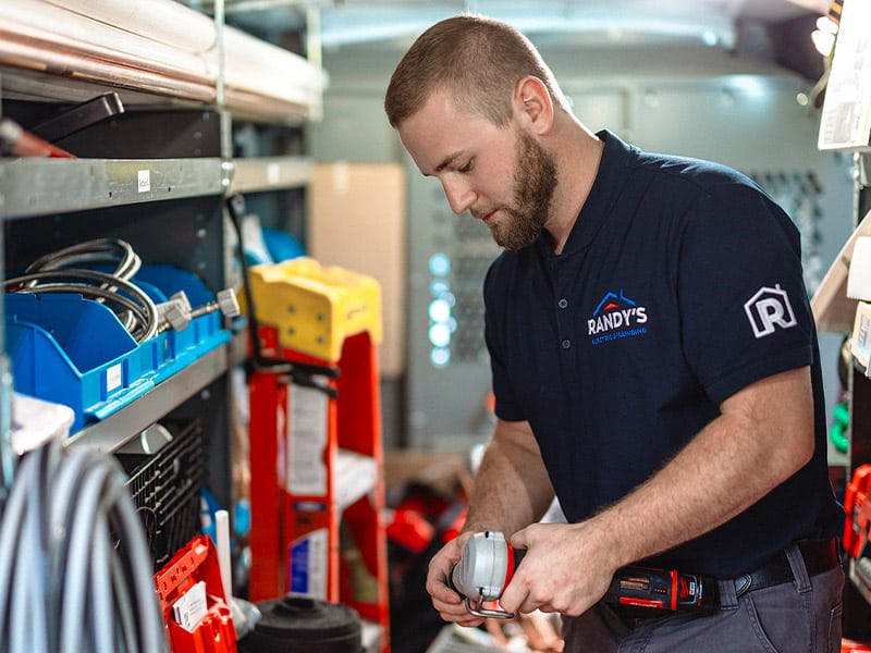 A person working in a van with tools, wearing a Randy's labeled shirt.